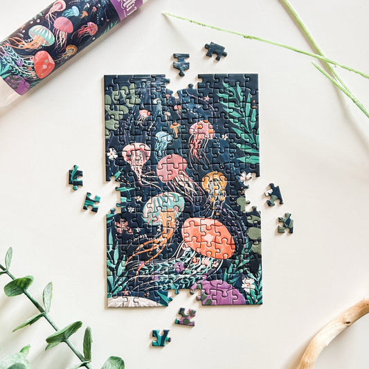 Jigsaw puzzle with jellyfish design on a white surface with green leaves.